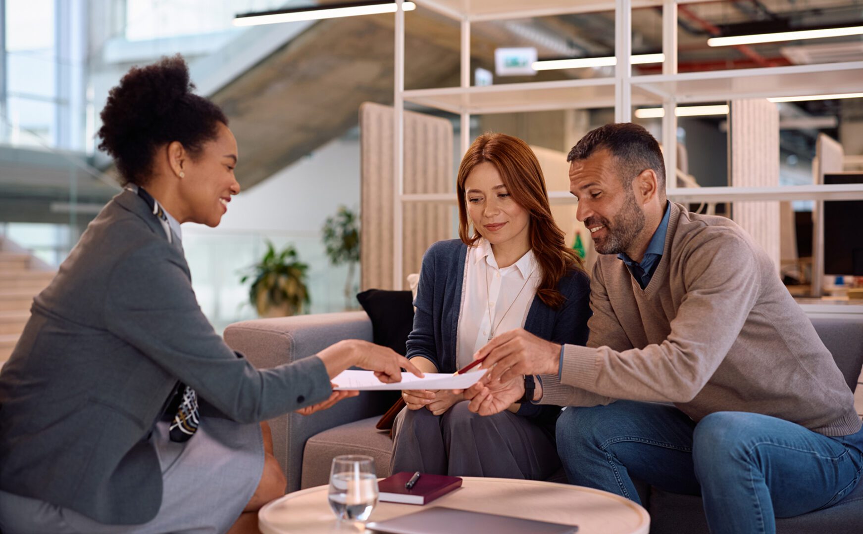 Three people discussing documents in an office.